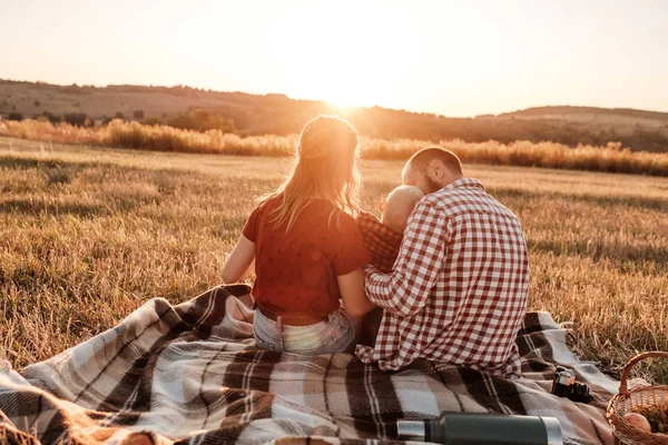 Szczęśliwa młoda rodzina mama i tata z ich małym synem korzystających letni weekend piknik poza miastem na polu w słoneczny dzień zachód słońca, wakacyjny czas Concept — Zdjęcie stockowe