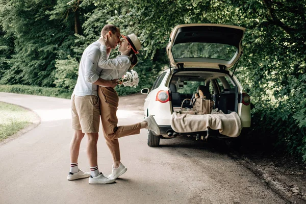 Beyaz tişörtlü genç mutlu çift arabanın yanında eğleniyor, hafta sonu şehir dışında, tatiller ve yolculuk konsepti. — Stok fotoğraf