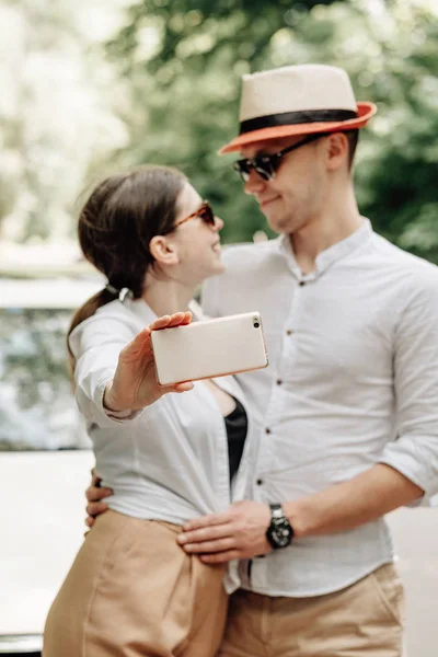 Joven Pareja Feliz Vestido Igual en Camiseta Blanca Sosteniendo Smartphone Cerca del Coche, Fin de Semana Fuera de la Ciudad, Vacaciones y Concepto de Viaje por Carretera — Foto de Stock