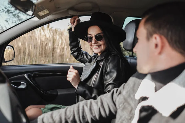 Happy Traveling Couple Dressed in Black Stylish Clothes Enjoying a Road Trip Sitting Inside the Car, Vacation Concept — Stock Photo, Image