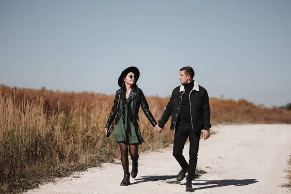 Ritratto di coppia felice vestita di abiti neri alla moda che si diverte a passeggiare sul campo — Foto Stock