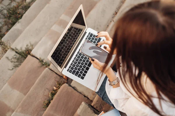 Retrato de uma menina na moda vestida de jeans e camisa branca trabalhando no laptop, trabalhador freelance, senhora de negócios, conceito de poder da mulher — Fotografia de Stock