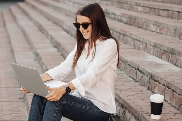 Retrato de uma menina na moda vestida em jeans e camisa branca segurando laptop, trabalhador freelance, senhora de negócios, conceito de poder da mulher — Fotografia de Stock