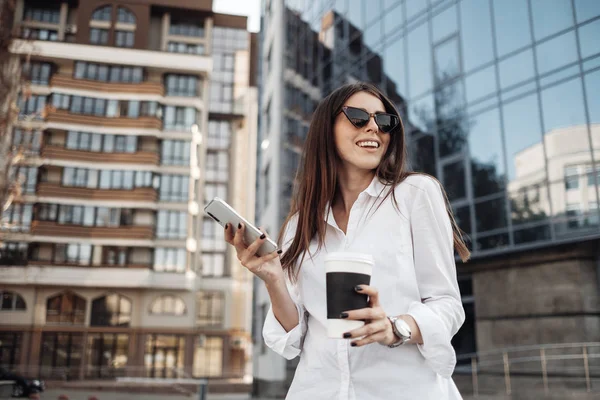 Retrato de uma menina na moda Vestida de Jeans e Camisa Branca Bebendo Café e Usando Seu Smartphone, Senhora de Negócios, Conceito de Poder da Mulher — Fotografia de Stock