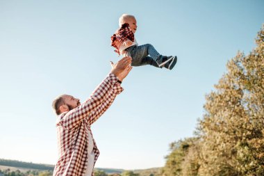 Küçük oğluyla mutlu bir baba. Yaz haftasının tadını çıkarıyor. Güneşli gün batımında şehrin dışındaki kırda.