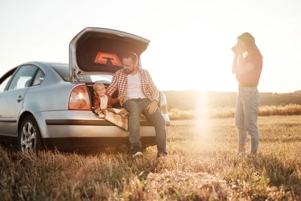 Glad ung familj mamma och pappa med sin lilla son Njuter av sommar helg picknick på bilen utanför staden i fältet på soliga dagen solnedgång, semester och väg resa koncept — Stockfoto