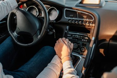 Beyaz gömlekli ve kot pantolonlu genç mutlu çift yeni arabalarında yolculuğun tadını çıkarıyor, Sahada güzel bir gün batımı, tatil ve seyahat konsepti