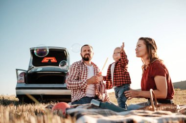 Mutlu Genç Aile Anne ve Baba ve Küçük Oğulları Yaz Haftasonu Pikniği Şehrin dışında, Baloncuklarla Oynuyor