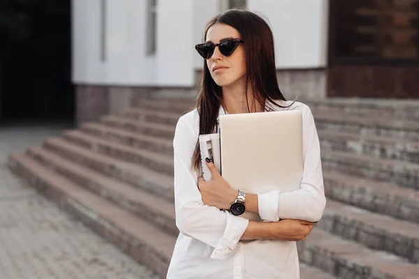 Retrato de una chica de moda vestida con vaqueros y camisa blanca que sostiene el ordenador portátil, trabajador independiente, dama de negocios, concepto de poder de la mujer — Foto de Stock