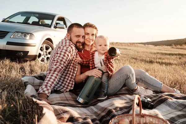 Happy Young Family Mom and Dad with Their Little Son Menikmati piknik akhir pekan musim panas Duduk di Plaid Near the Car Outside the Field at Sunny Day Sunset, Vacation and Road Trip Concept — Stok Foto