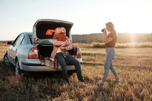 Szczęśliwa młoda rodzina Mama i tata z ich małym synem korzystających letni piknik weekendowy na samochodzie poza miastem na polu w słoneczny dzień zachód słońca, wakacje i Road Trip Concept — Zdjęcie stockowe