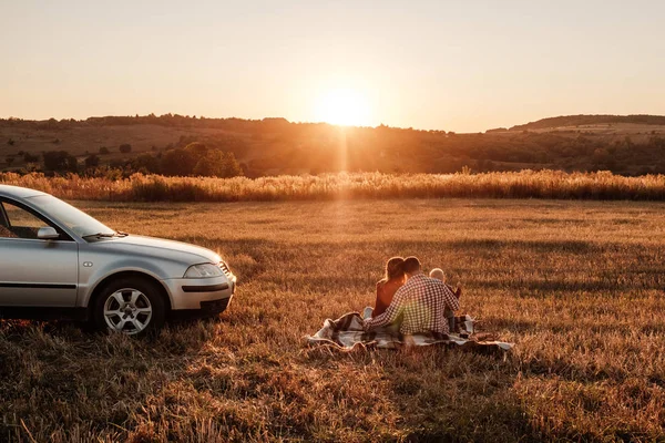 Glad ung familj mamma och pappa med sin lilla son Njuter av sommar helg picknick på bilen utanför staden i fältet på soliga dagen solnedgång, semester och väg resa koncept — Stockfoto