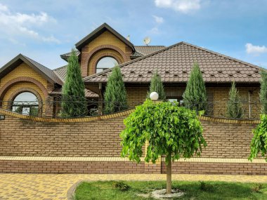 Yeşil çimenlerin içinde taş yol. Peyzaj parkından geç. Yol boyunca ağaç.