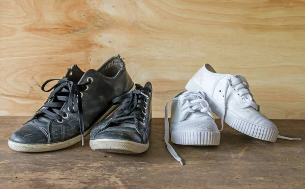 Czarne buty i białe buty na podłoże drewniane — Zdjęcie stockowe