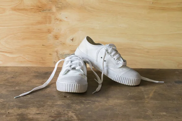 Antika ahşap arka plan üzerinde beyaz öğrenci Ayakkabı — Stok fotoğraf