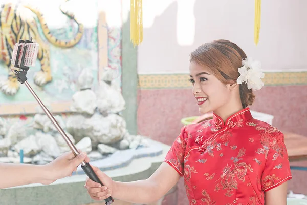 Улыбающаяся азиатка делает фото с селфи-палкой — стоковое фото