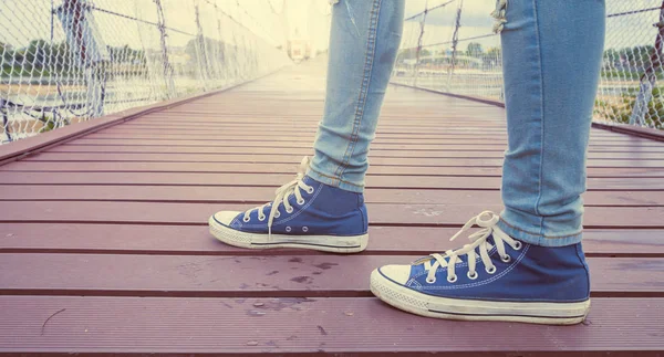 Sneaker shoes and blue jeans on the bridge — Stock Photo, Image