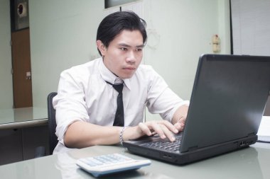 Asyalı iş adamı dizüstü bilgisayarla çalışıyor