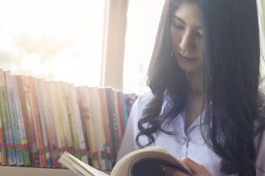 Asyalı öğrenci libraly odasında bir kitap okuma