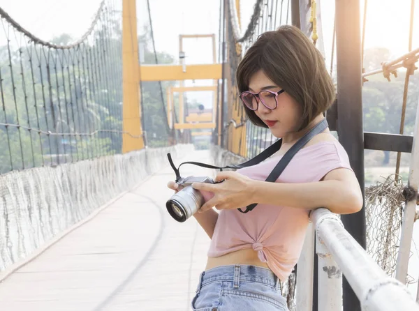 Porträtt av vacker asiatisk kvinna som håller och tittar på sin kamera — Stockfoto