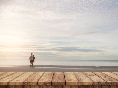 Bulanık kumsalda ahşap masa üstü bazı insanlarla dolu.