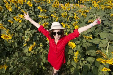 Çiçek açan ayçiçeği tarlasında şapkası olan genç Asyalı kadın.