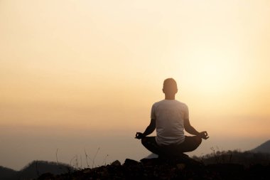 Siluet Asyalı adam yogası günbatımında.