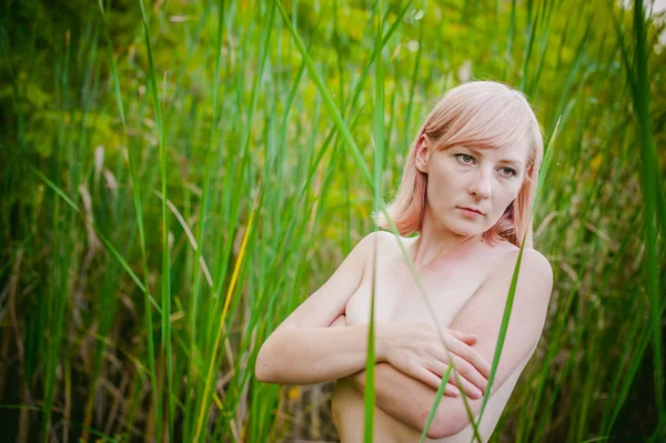 Menina nua em sedge. jovem loira com seios nus, envolto em um pano vermelho, de pé nos juncos — Fotografia de Stock