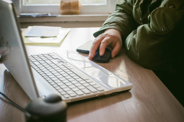 Hombre adulto con bigote y gafas, trabajando en una computadora, sosteniendo un ratón en sus manos . — Foto de Stock