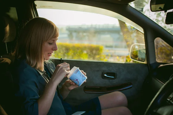 Chica comiendo helado con una cuchara en el coche — Foto de Stock