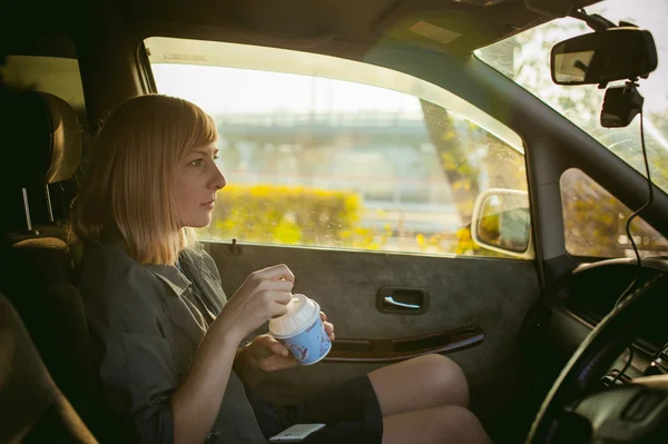 Девушка ест мороженое с ложкой в машине — стоковое фото