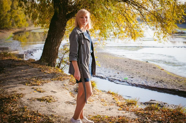 Photo jolie fille blonde sur le fond des feuilles d'automne jaunes tombées — Photo