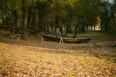 Güzel sarışın oturan sarı düşmüş sonbaharda koydu yerde olan bir ahşap gemi kalkıyor