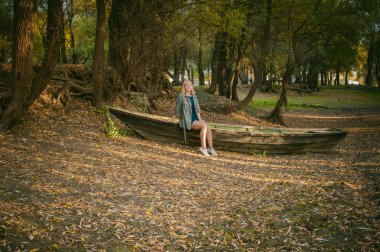 Güzel sarışın oturan sarı düşmüş sonbaharda koydu yerde olan bir ahşap gemi kalkıyor