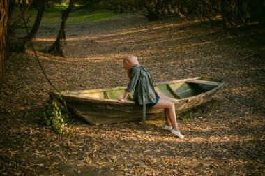 Güzel sarışın oturan sarı düşmüş sonbaharda koydu yerde olan bir ahşap gemi kalkıyor