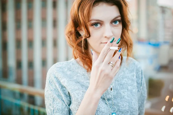 Uma rapariga com um cigarro. jovem bela mulher fuma um cigarro na rua — Fotografia de Stock