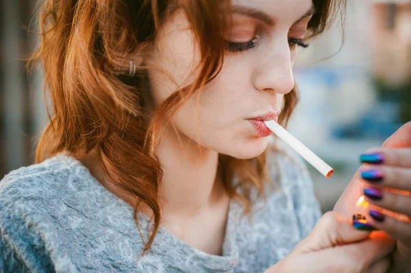 Uma rapariga com um cigarro. jovem bela mulher fuma um cigarro na rua — Fotografia de Stock