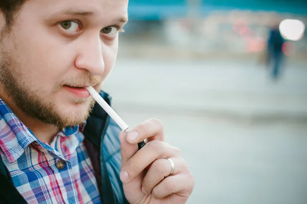 Fumar cigarrillos. un hombre con barba fuma un cigarrillo en la calle en un lugar público . — Foto de Stock