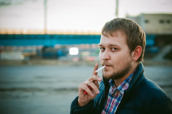 Fumar cigarrillos. un hombre con barba fuma un cigarrillo en la calle en un lugar público . — Foto de Stock