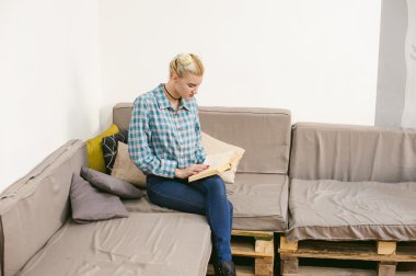 genç güzel kız odasında bir kanepede oturan bir kitap okuma