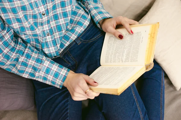 Genç güzel kız odasında bir kanepede oturan bir kitap okuma — Stok fotoğraf