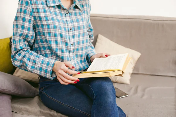Genç güzel kız odasında bir kanepede oturan bir kitap okuma — Stok fotoğraf