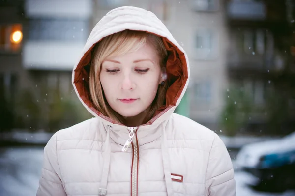 Blonde girl in the yard of a house. the first snow in the city — Stock Photo, Image