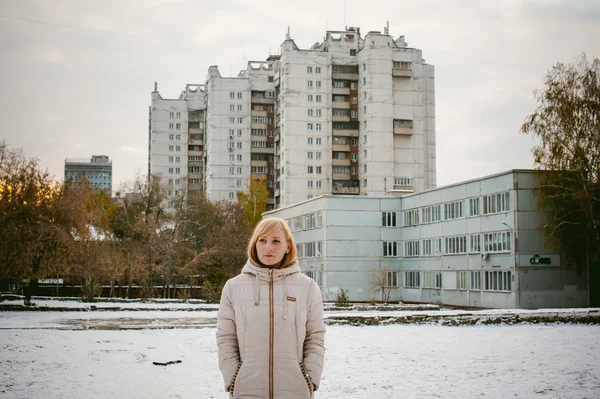 Blond meisje in de tuin van een huis. de eerste sneeuw in de stad — Stockfoto