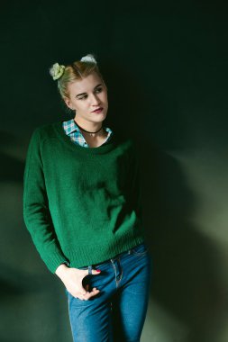 Stüdyo bir kız portresi. Yeşil kazak ve mavi jeans, odada iken hipster genç güzel kadın