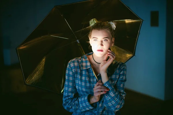 Studioporträt einer jungen Frau mit goldenem Regenschirm — Stockfoto