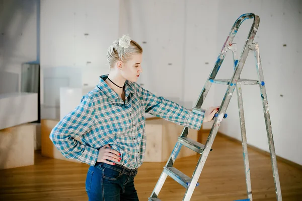 girl and construction ladder. studio shot of a young woman with a construction ladder in the room
