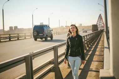 Kız yolu köprüsü üzerinde gider. taşıma gider köprüden yürüyen yalnız genç kadın siyah deri ceket Güz,.