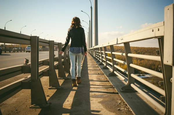 Kız yolu köprüsü üzerinde gider. taşıma gider köprüden yürüyen yalnız genç kadın siyah deri ceket Güz,.