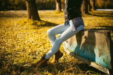 Mavi kot pantolon ve kahverengi botları kızın bacakları ince. kalkık teknede shore, sarı sonbahar yaprakları kız oturdu